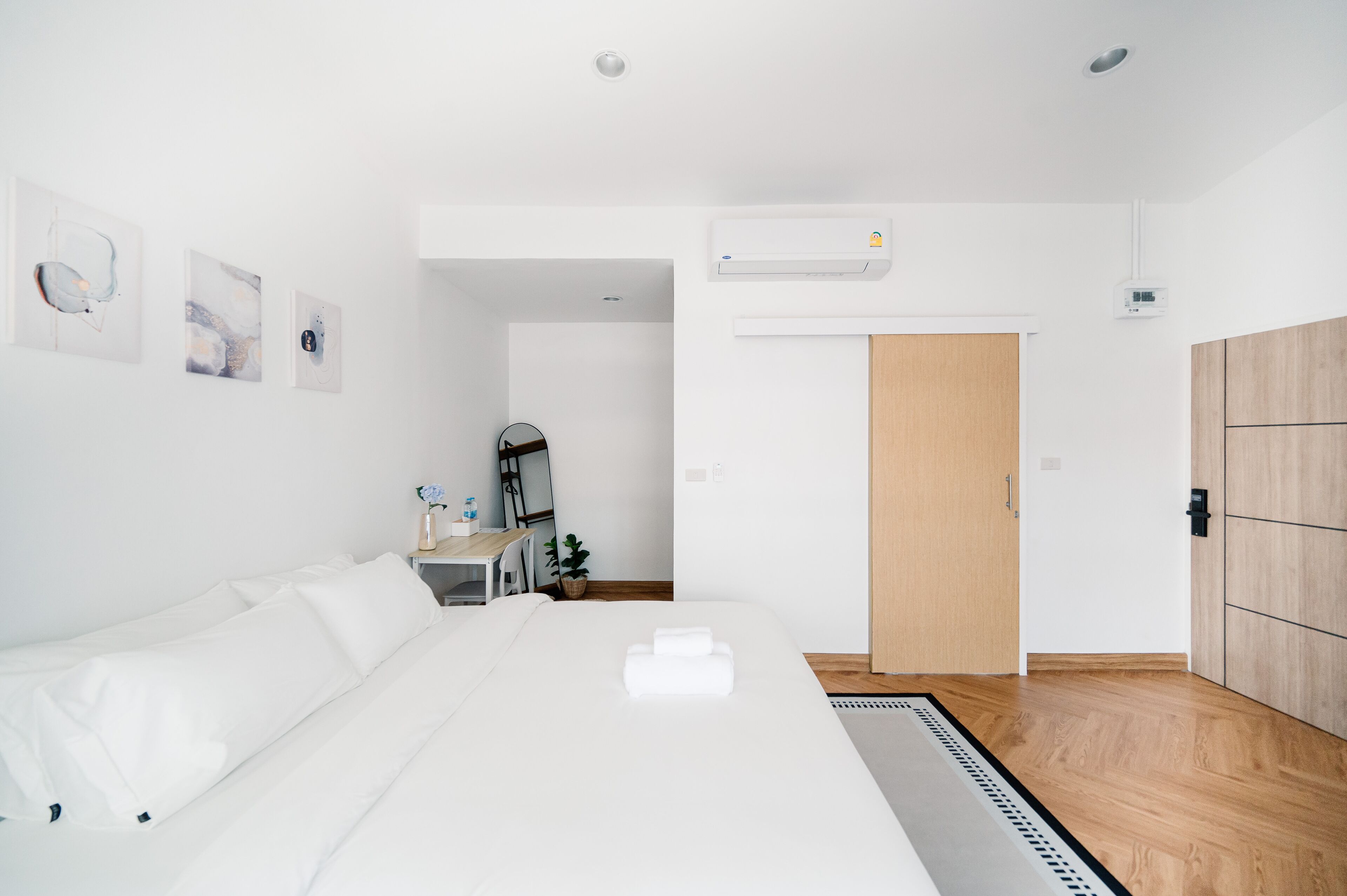 A modern hotel room with a large bed, a desk, and a wardrobe.