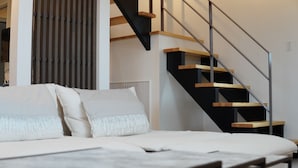 Un dormitorio moderno con cama, una escalera de madera y vistas a un paisaje urbano.