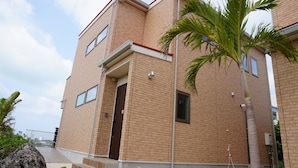 Un edificio de ladrillo de varios pisos con techo plano, una puerta a la vista y una ventana pequeña.