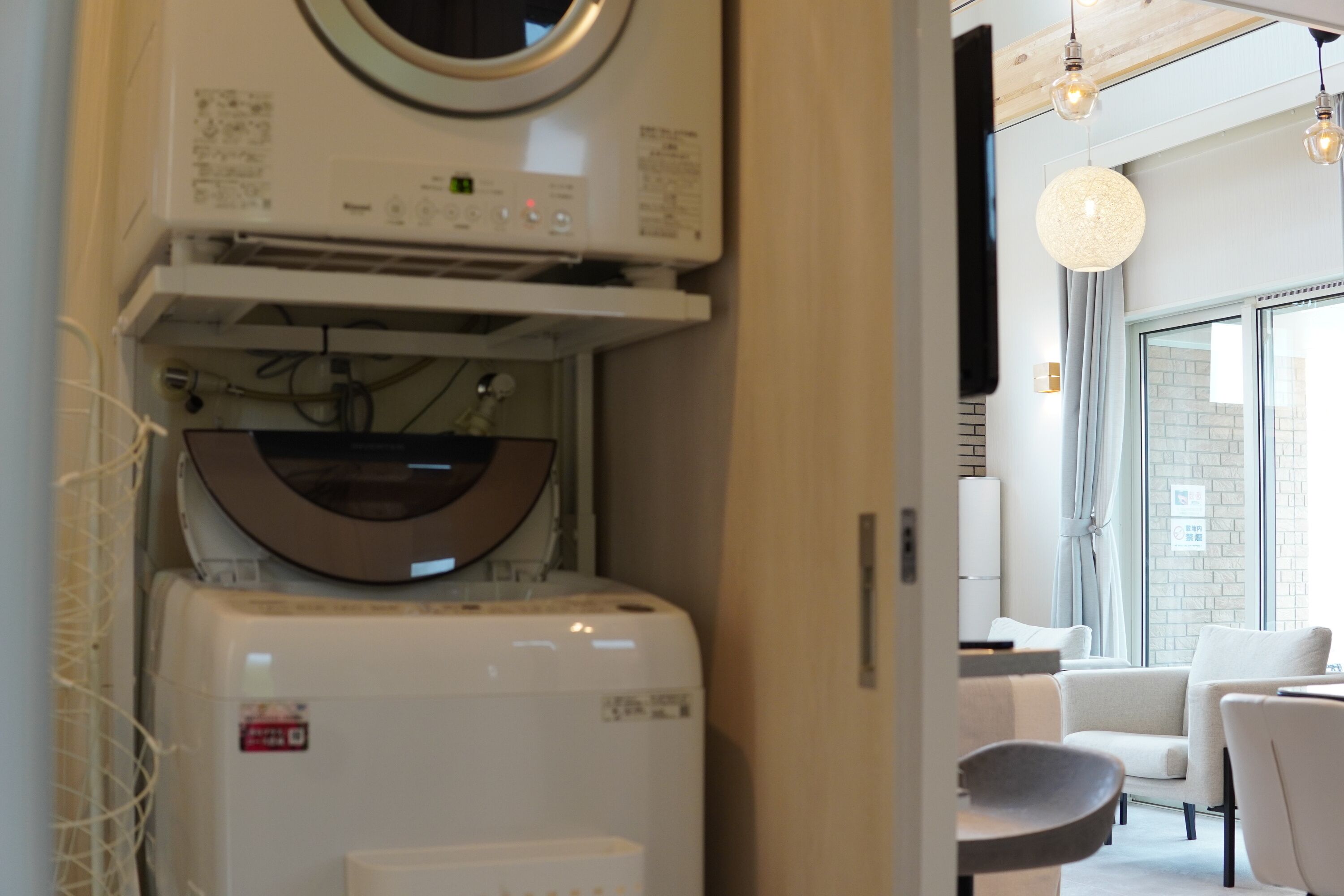 Una habitación moderna con lavadora y secadora integradas, una lámpara redonda y vistas al exterior a través de amplias ventanas.