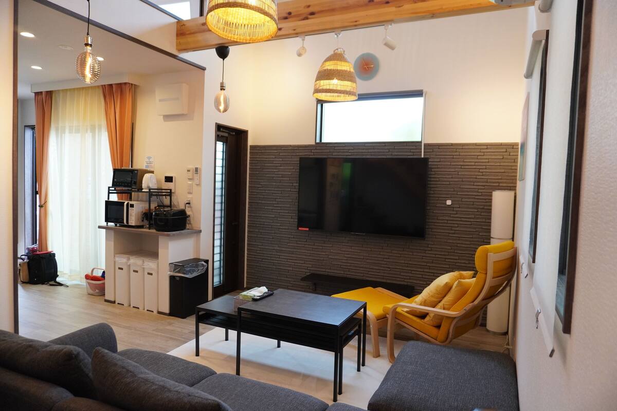 A modern living room with a flat-screen TV, a coffee machine, and a dining area.