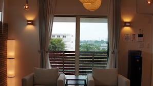 Una habitación moderna con un ventanal grande, dos sofás, una mesita y una lámpara en el techo.