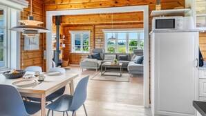 Un intérieur de chalet chaleureux comprenant un coin repas, un salon avec un canapé et une cuisine équipée d’un four à micro-ondes.