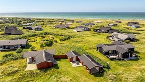 Vue aérienne d’un quartier résidentiel situé sur la côte, avec des maisons à l’architecture moderne, dont certaines sont dotées de garages attenants, et qui offrent une vue dégagée sur l’océan.