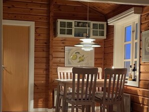 Cozy cabin interior with a dining area featuring a wooden ceiling, white-framed window, and wooden paneling.
