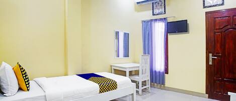 A bedroom with a bed, a desk, a chair, an air conditioning unit, and a door.