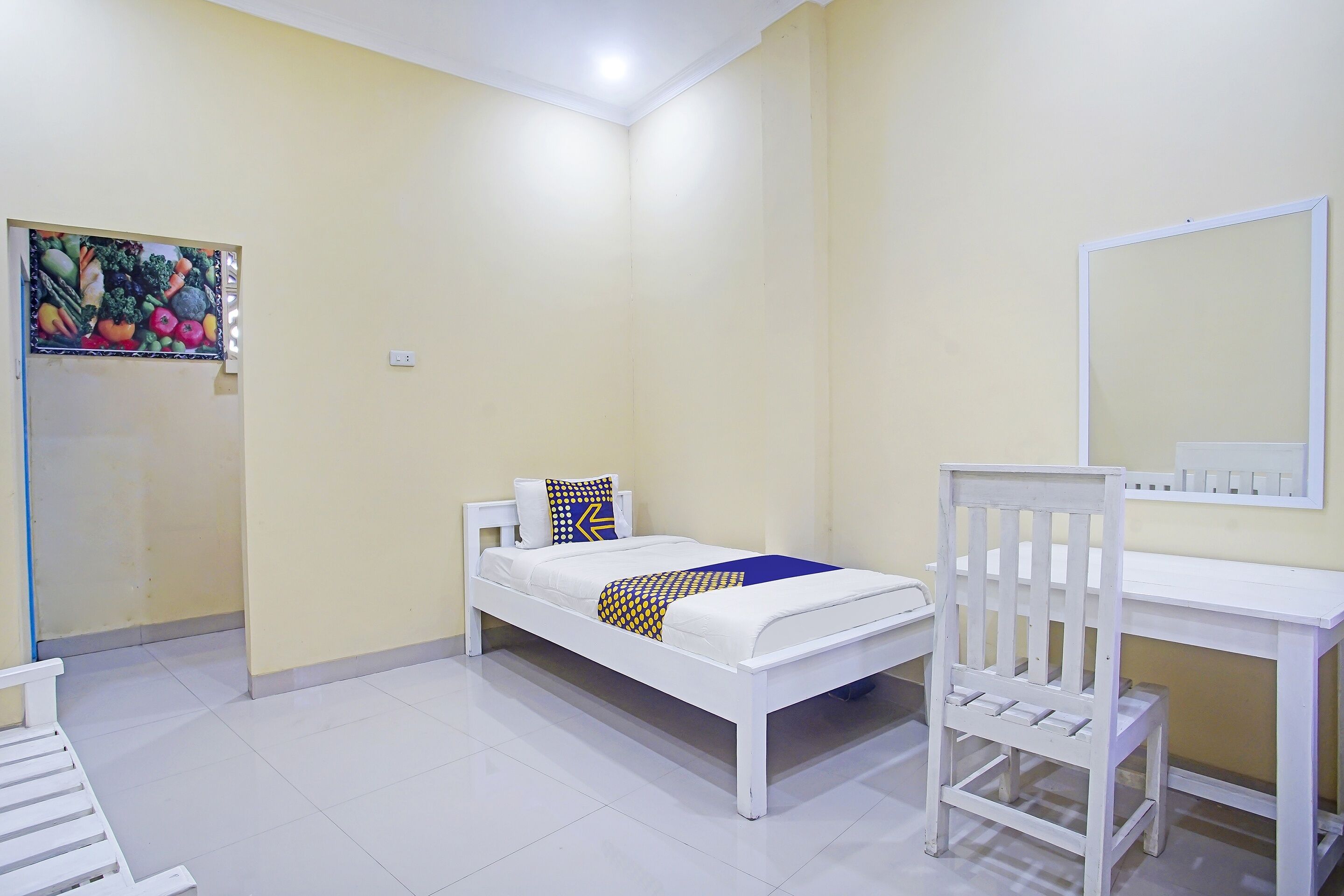 A bedroom with a bed, a desk, a chair, and a mirror.