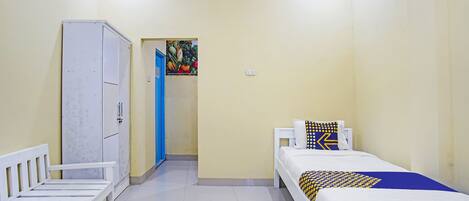 Een kamer met een bed, een kledingkast en een deur naar een andere ruimte.