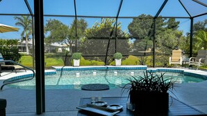 Un espace piscine doté d’une structure en verre, d’une table de billard et de chaises longues.