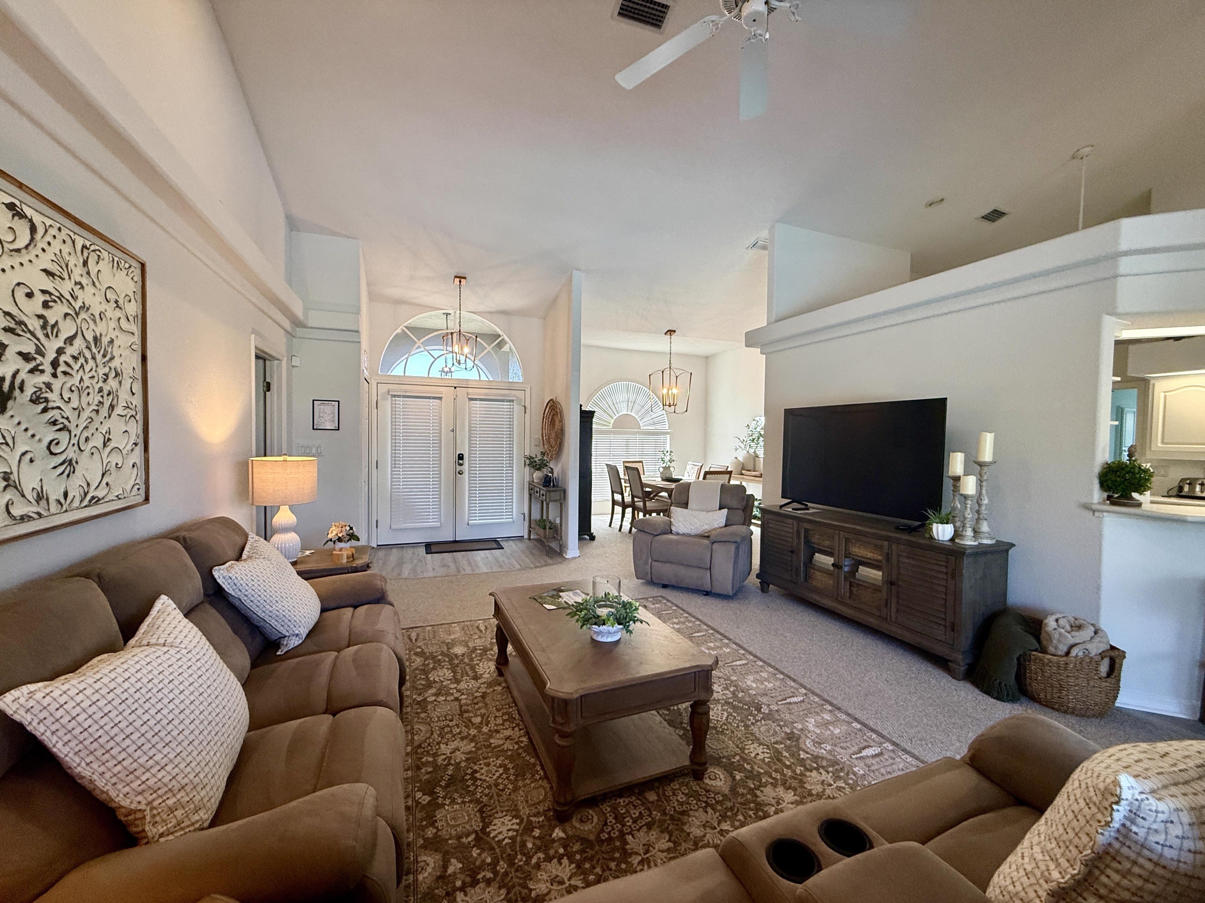 A spacious living room with a large television, comfortable seating, and a decorative rug.