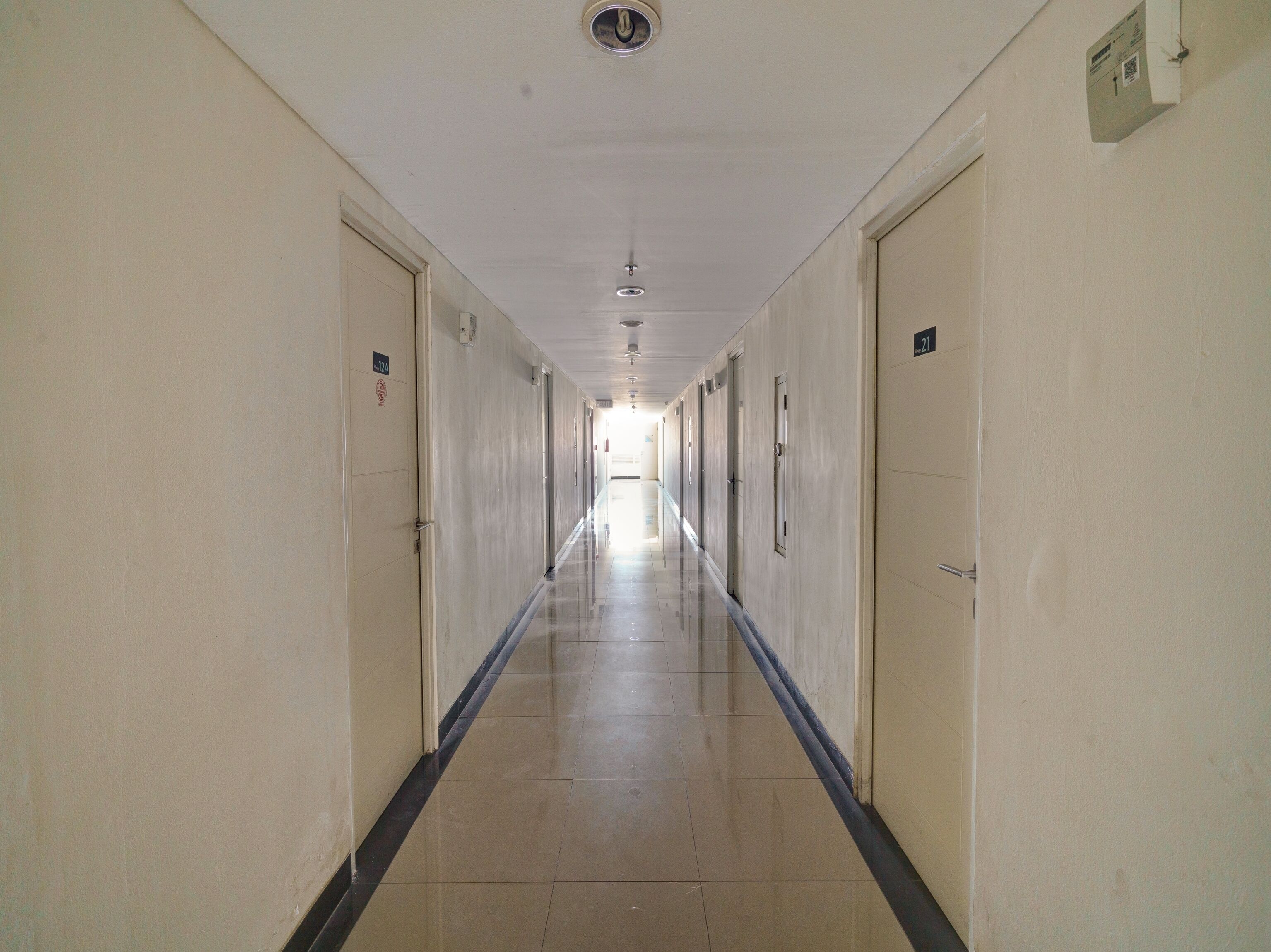 Un largo pasillo estrecho con puertas a ambos lados, que conduce a habitaciones individuales.