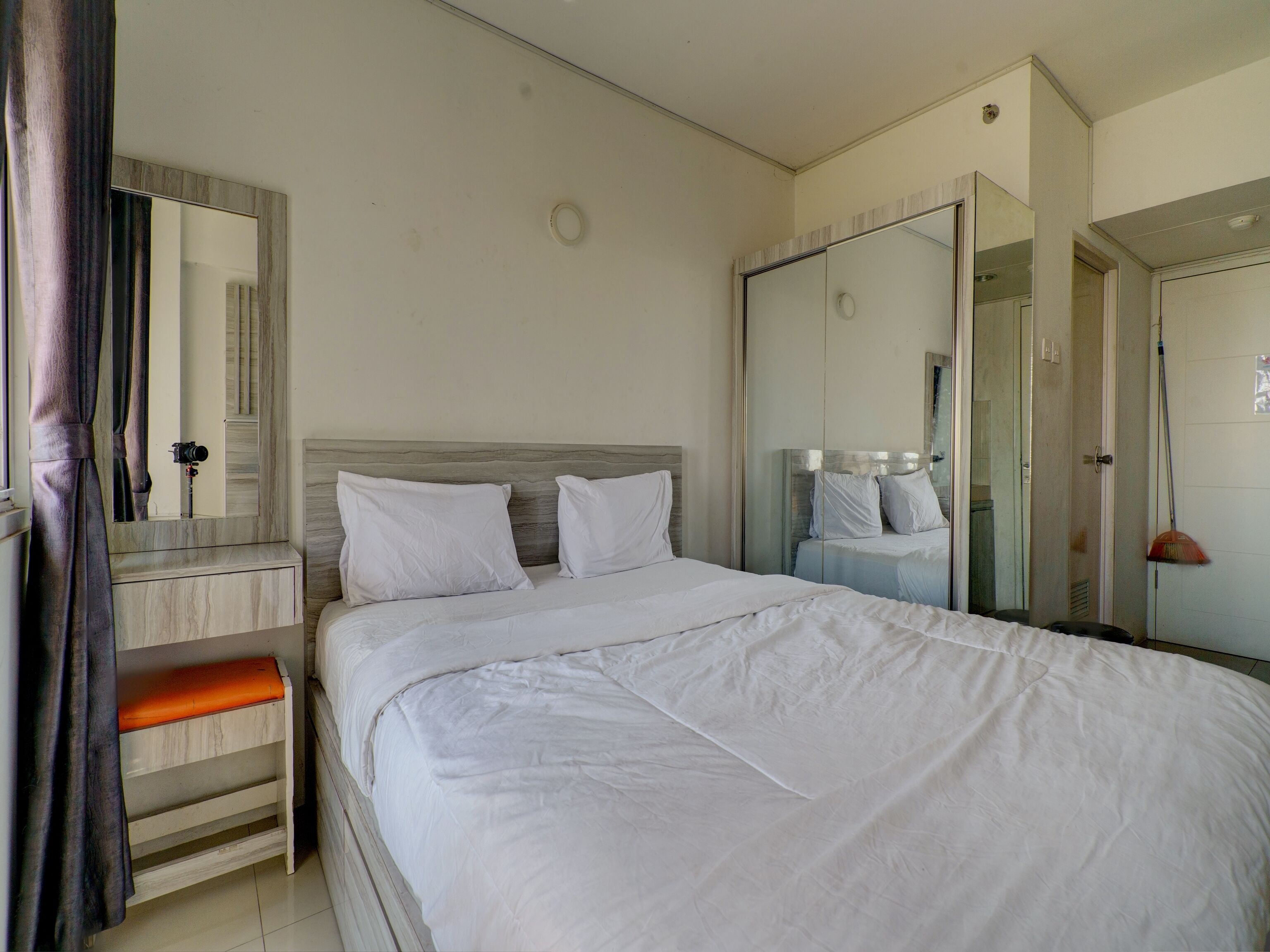 Ein Schlafzimmer mit einem großen Bett, einem Spiegel, einem Kleiderschrank und einer Badezimmertür.