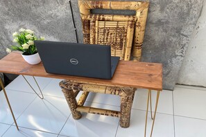 A laptop on a wooden table with a white pot of flowers. - OYO Life 93125 Kos Bale Lumbung Syariah (Tanjung)