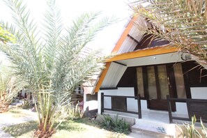 A building with a sloped roof, a wooden porch, and a stone foundation. - OYO Life 93125 Kos Bale Lumbung Syariah (Tanjung)