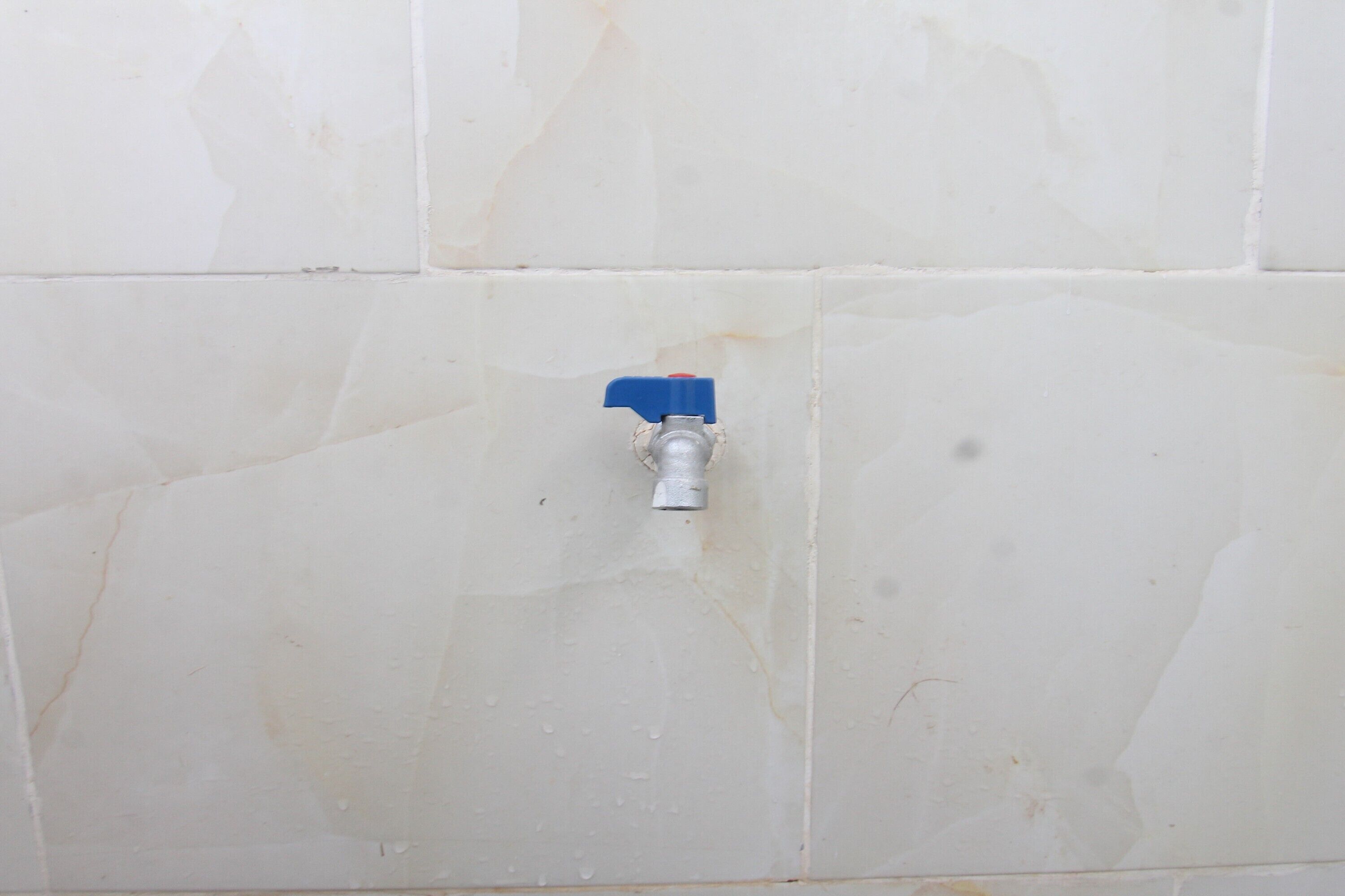 Ein Badezimmer mit weißen Fliesenwänden und sichtbarer Sanitärinstallation.