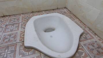 Un inodoro con un tazón de cerámica blanca y un suelo de baldosas estampadas.