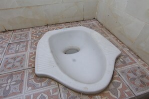 A toilet with a white ceramic bowl and a patterned tile floor. - OYO Life 93125 Kos Bale Lumbung Syariah (Tanjung)