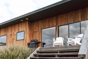Un edificio moderno con paneles de madera, ventanas amplias y zona de estar al aire libre.