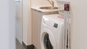Ein kleiner Hauswirtschaftsraum mit Waschmaschine und Trockner, einem Waschbecken und einer kleinen Arbeitsfläche.