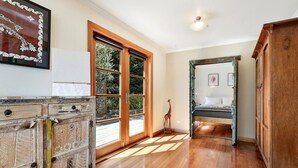Una stanza con pavimento in legno, un letto con copriletto decorato, una statua di giraffa e un'ampia finestra vista su del verde.
