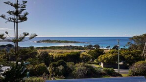 A coastal landscape with a clear view of the sea, a beach, and a road leading to a building. - Lucy (Glamorgan-Spring Bay)