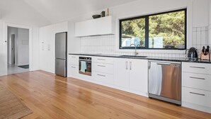 A modern kitchen with white cabinets, stainless steel appliances, and a large window. - Lucy (Glamorgan-Spring Bay)