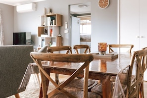 Enjoy meals in this cozy dining area with a wooden table and chairs, a bookshelf, and a clock on the wall.
