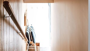 A modern interior with a wooden slat wall, a hanging light fixture, and a view of a staircase leading to a balcony. - The Barn - Georges Bay, St Helens (Break O'Day)