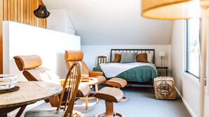 A modern bedroom with a bed, seating area, and a window. - The Barn - Georges Bay, St Helens (Break O'Day)