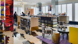 A modern bar area with a bar counter, seating, and a large abstract painting. - Apt 2505 · Brickell Icon STUDIO (Miami)
