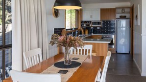 Een moderne keuken met houten kastjes, een centraal eiland en een eetgedeelte met een houten tafel en witte stoelen.