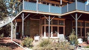Un bâtiment à deux étages doté d’un patio couvert, d’un chemin en briques et d’un petit jardin.