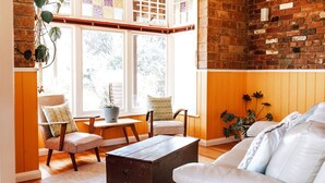 A cozy living room with a white sofa, two armchairs, a wooden coffee table, and a brick wall. - The most beautiful guest retreat (Break O'Day)