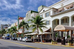 A street view with a row of buildings, including a restaurant named 'The Betsy' with outdoor seating and a covered area.
