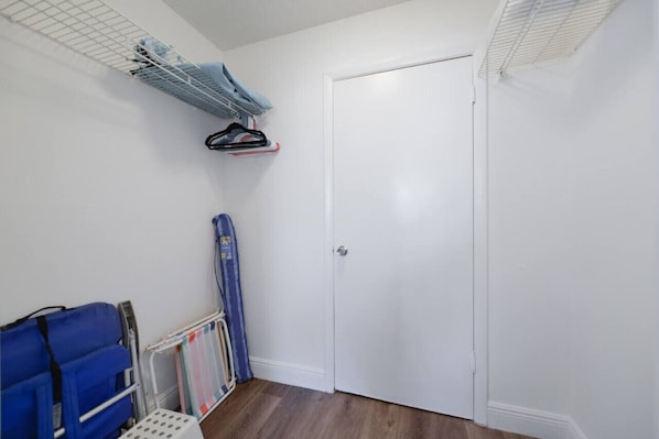 A room with a white door, a blue chair, a drying rack, and a blue towel on the wall.