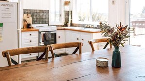 A kitchen with wooden chairs, a dining table, and a vase with flowers. - sloop cottage | beachfront | vibes (Break O'Day)