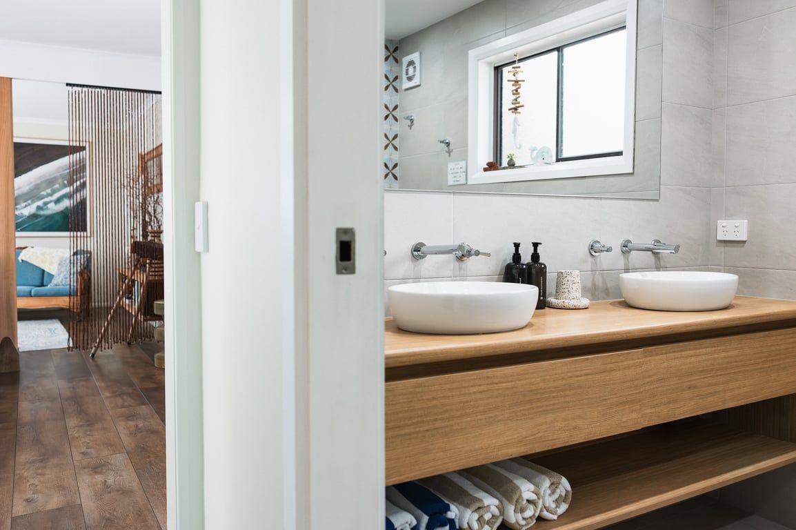 Een moderne badkamer met twee wasbakken, een spiegel en een raam.