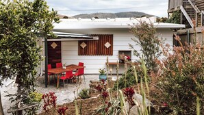 A white house with a wooden deck, red chairs, and a table. - KAL's House - The place to be! (Glamorgan-Spring Bay)