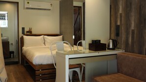 Une chambre d’hôtel de taille réduite, comprenant un lit, un bureau, une chaise, un canapé et un miroir.