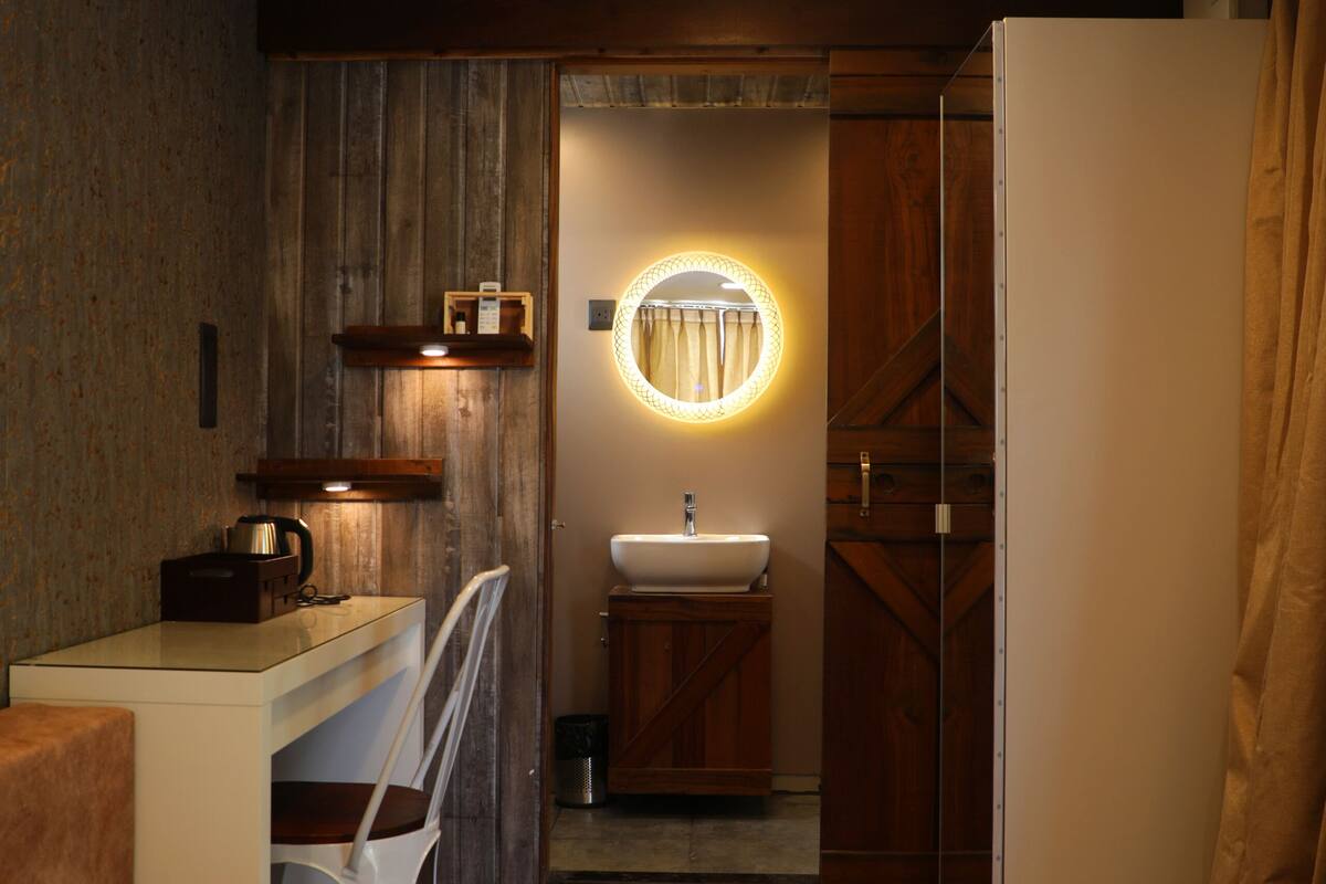 A compact, modern bathroom with a wooden vanity, a sink, and a mirror with a circular light.