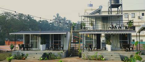 A two-story building with a patio area, outdoor seating, and a water tank on the roof.