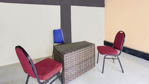 A small room with a table and two chairs, one blue and one red. - OYO Life 93155 Wisma Sarah (Tanjung)