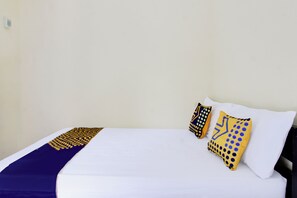 A bed with white linens, a blue and gold patterned throw, and two decorative pillows with geometric designs. - OYO Life 93155 Wisma Sarah (Tanjung)