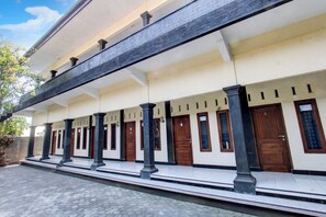A building with a series of doors and windows, a tiled ground, and a clear sky. - OYO Life 93155 Wisma Sarah (Tanjung)
