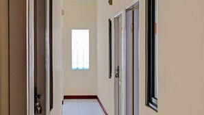A hallway with a tiled floor, a window, and doors. - OYO Life 92546 Kost Merah Bojongsoang Syariah (Bojongsoang)