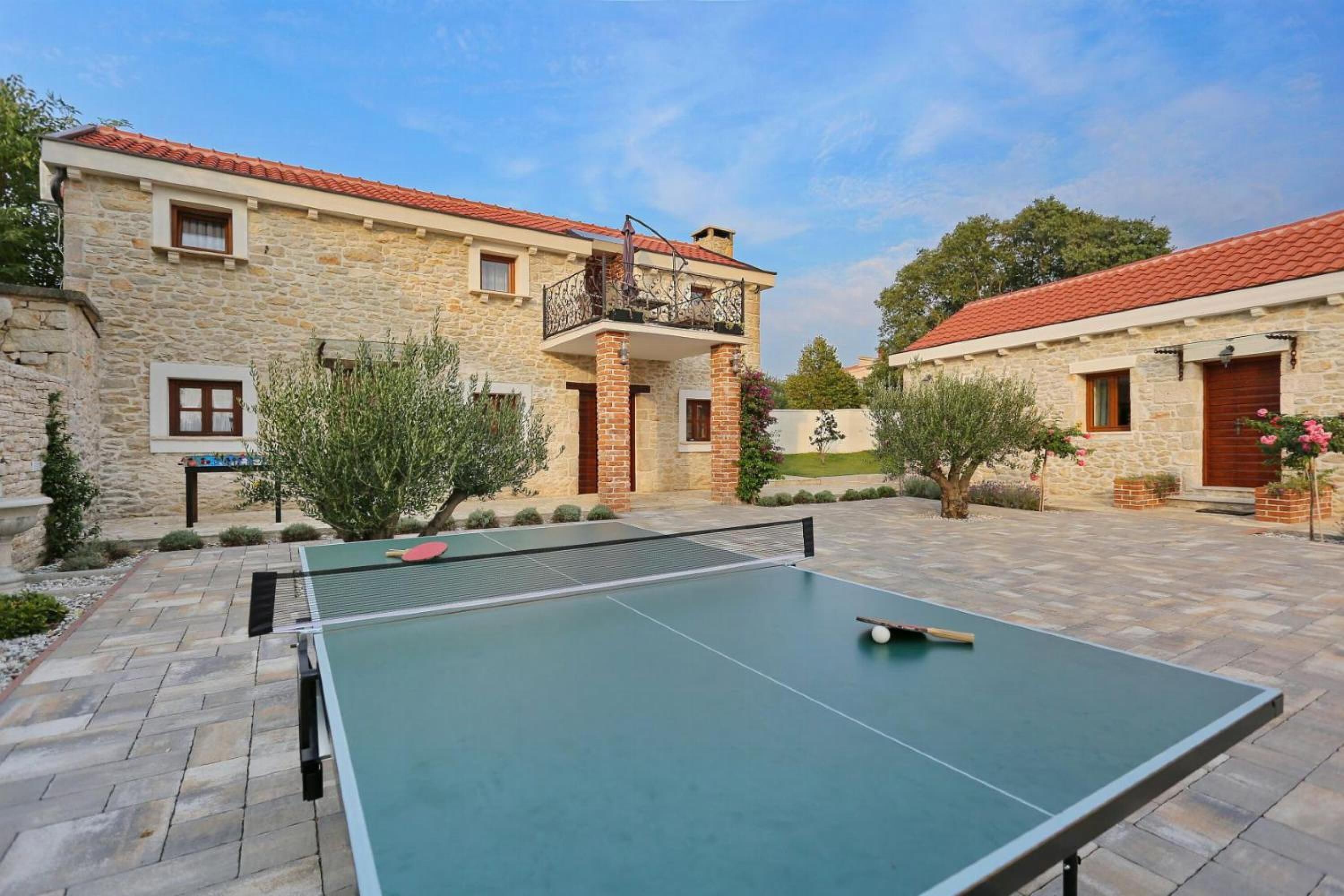 A courtyard with a ping pong table, stone buildings, and a red-tiled roof.