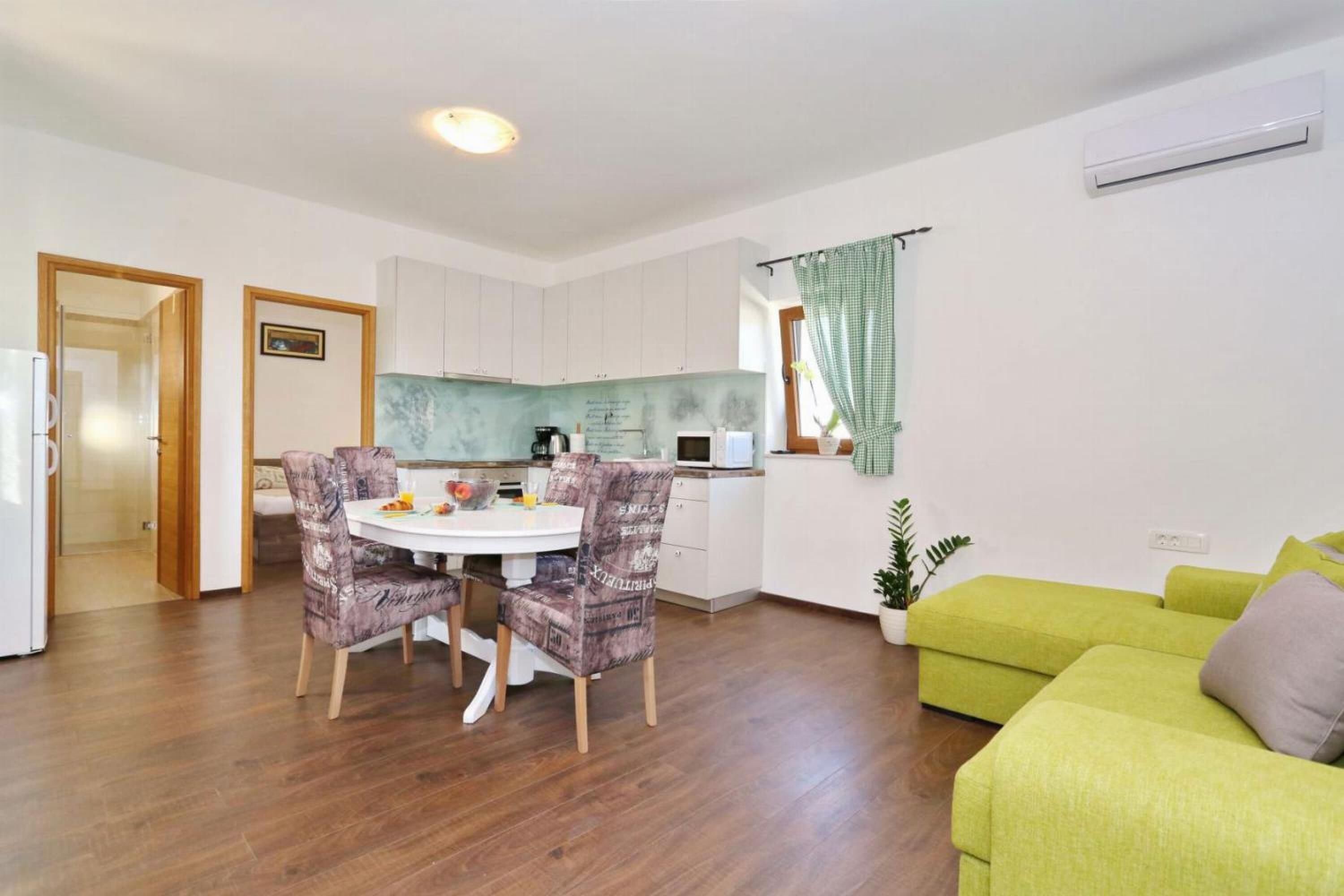 A compact living space with a dining area, kitchenette, and a green sofa.