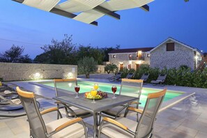 An outdoor pool area with lounge chairs and a table set with fruit and wine glasses. - Villa Tereza in Prkos (Škabrnja)
