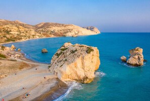 A coastal landscape with rocky formations and a beach. - Villa Sunlove in Peyia (Pegeia)