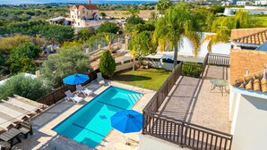 A rooftop pool with lounge chairs and umbrellas, surrounded by greenery and a view of the sea. - Villa Sunlove in Peyia (Pegeia)